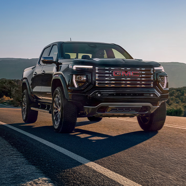 The 2025 GMC Canyon Denali Truck Driving Down the Road in the Mountains