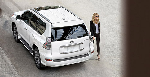 Upper rear view of Lexus GX with lady walking beside it