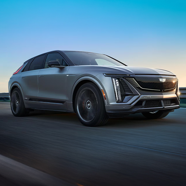 Three-quarter Passenger Side View of a Silver 2026 Cadillac LYRIQ-V Electric SUV Driving Down a Road