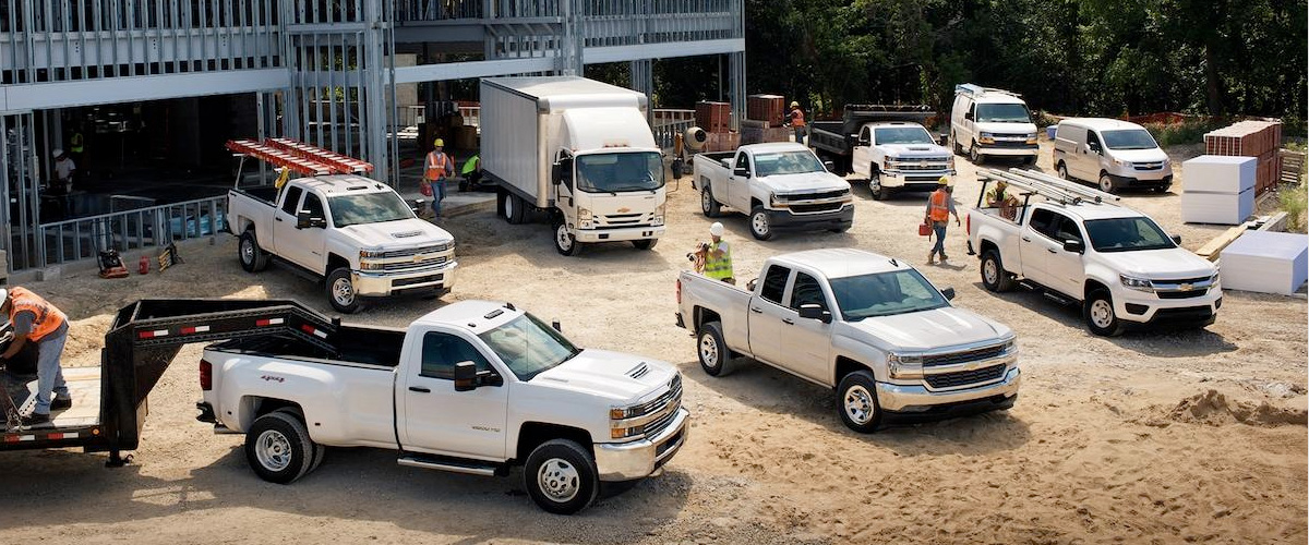 LINEUP OF CHEVROLET COMMERCIAL VEHICLES ON A WORK SITE